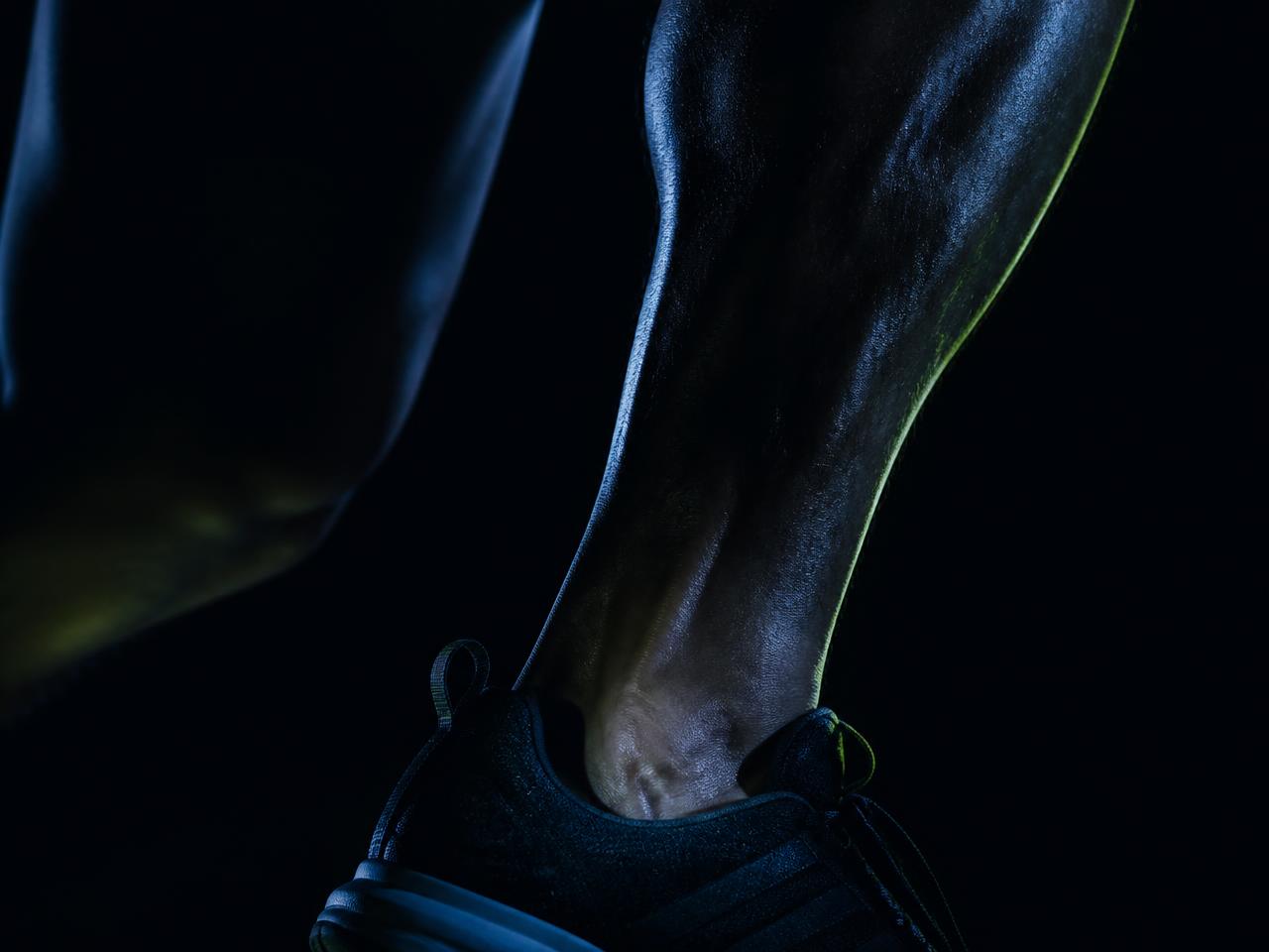 Close-up of an athlete's ankle in dark, moody light